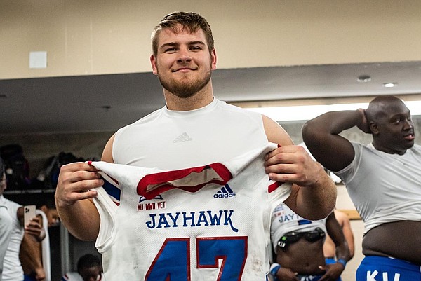 Kansas tight end Jared Casey holds up his No. 47 jersey in the visitors locker room after making the game-winning catch on a two-point conversion at Texas, on Nov. 13, 2021.
