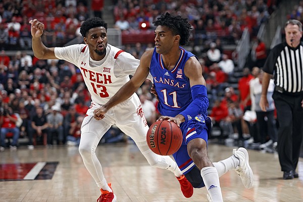 Kansas' Remy Martin (11) dribbles the ball around Texas Tech's Mylik Wilson (13) during the second half of an NCAA college basketball game on Saturday, Jan. 8, 2022, in Lubbock, Texas. (AP Photo/Brad Tollefson)