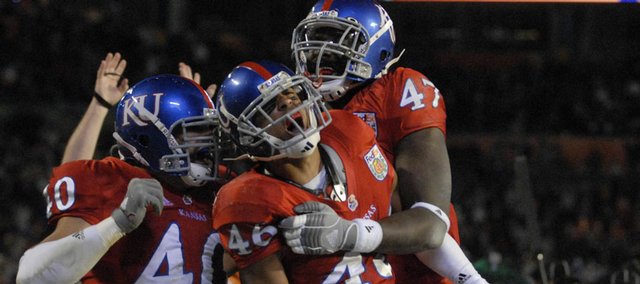 Kansas safety Justin Thornton, center, celebrates with Mike Rivera, left, and Maxwell Onyegbule following his interception during the second half. The pick helped the Jayhawks beat Virginia Tech, 24-21, in the Orange Bowl on Thursday in Miami.