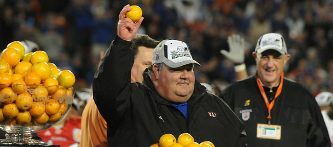 Kansas coach Mark Mangino holds aloft an orange as KU athletic director Lew Perkins, right, looks on.