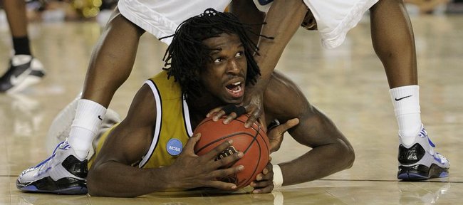 Missouri's DeMarre Carroll gets the ball and a bloodied lip as his slides under Memphis' Robert Dozier during the second half of a men's NCAA college basketball tournament regional semifinal in Glendale, Ariz., Thursday, March 26, 2009.