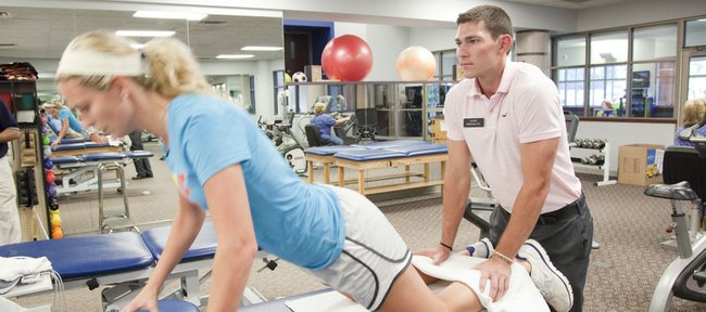 Kansas University guard Tyrel Reed works with Jenna Brantley, a Baker University senior guard who tore her ACL, Monday at OrthoKansas. Reed, an exercise science major, is interning with Lawrence physical therapist Randy Freivogel.