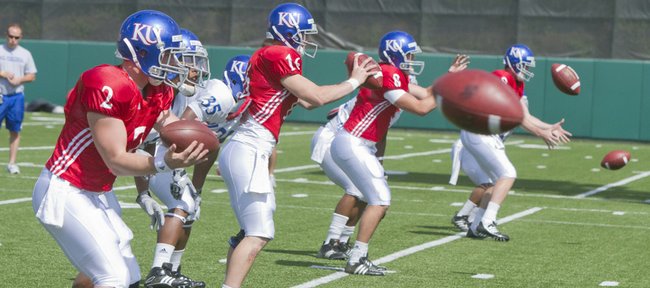Kansas University quarterback Quinn Mecham (8) works on taking snaps, alongside Jordan Webb (2), Jacob Morse (16) and Conner Teahan, far right, on April 19 at a spring practice at Memorial Stadium. Turner Gill has options but has not named a starting quarterback for the game against Colorado.