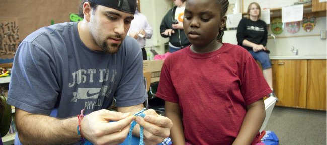 Former Kansas University football player and current Miami Dolphins linebacker Mike Rivera, left, sits with Boys and Girls Club member Frida Danburno as the two work on a crochet project. Rivera volunteered his time to city youths on Wednesday, April 13, 2011 at Hillcrest Elementary.