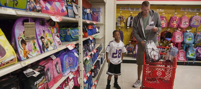 Oklahoma City Thunder center and former Kansas University player Cole Aldrich, right, checks a list of school supplies he planned on buying for Isaiah Mayo, 8. Aldrich and Target purchased $1,000 worth of school supplies for city youths Monday at SuperTarget, 3201 Iowa Street.