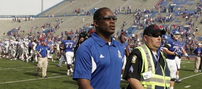 Kansas head coach Turner Gill is escorted by security from the field following the Jayhawks' 59-21 loss to rival Kansas State on Saturday, Oct. 22, 2011 at Kivisto Field.
