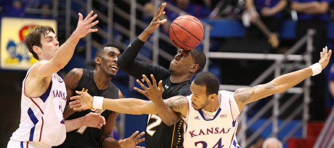 Kansas players Conner Teahan, left, and Travis Releford tangle with Towson players Marcus Damas, left, and Enrique Gumbs as the teams vie for a loose ball during the second half on Friday, Nov. 11, 2011 at Allen Fieldhouse.