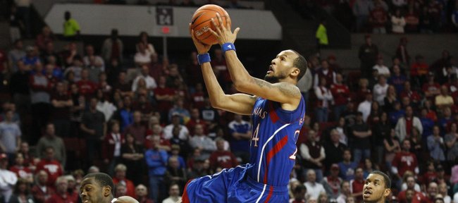 Kansas guard Travis Releford glides for a bucket between Oklahoma defenders Sam Grooms, left, and Steven Pledger during the second half Saturday, Jan. 7, 2012, at Lloyd Noble Center.