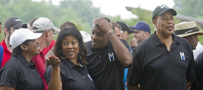 Former KU basketball player Mario Chalmers, now a member of the Miami Heat, second from right, and family members get wet during a rainfall before the start of the Mario Chalmers Foundation National Championship Classis golf tournament Friday, July 13, 2012, at Alvamar. Family members from left, all of Miami, are Almaire Chalmers, Mario's mother, his sister Roneka, Mario and his father Ronnie.
