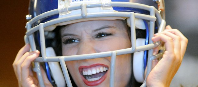 Kansas cheerleader Jordan Snyder jokes around with friends while wearing a football helmet at the Big 12 college football media days on Tuesday, July 24, 2012, in Dallas.