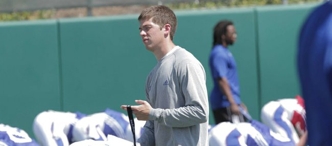 Charlie Weis Jr. walks through players stretching prior to Monday's practice at the KU practice fields.