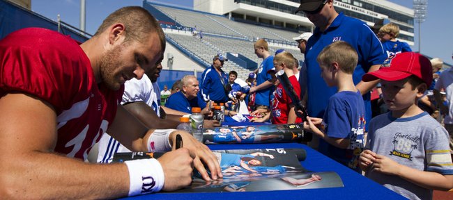 Greyson Heinan, 6, Lawrence, watches as Kansas quarterback Dayne Crist signs a poster during the autograph portion of Fan Appreciation Day on Saturday, Aug. 11, 2012, at Memorial Stadium.
