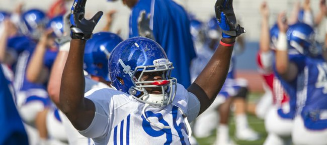 Kansas defensive lineman Keba Agostinho stretches during warm-up exercises at the Fan Appreciation Day open practice Saturday, Aug. 11, 2012, at Memorial Stadium. 