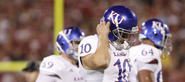 Kansas quarterback Dayne Crist unsnaps his helmet as he comes off the field during the second quarter on Saturday, Oct. 20, 2012 at Memorial Stadium in Norman.