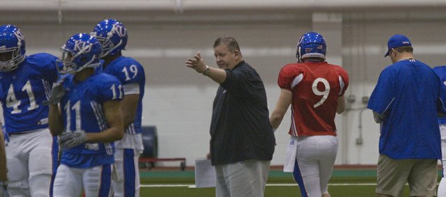 Kansas University football coach Charlie Weis, center, directs tight end Jimmay Mundine (41), receivers Tre’ Parmalee (11) and Justin McCay (19) and quarterback Jake Heaps (9) during spring drills on March 9, 2013, at Anschutz Sports Pavilion.