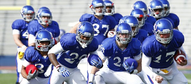 Kansas University running backs and quarterbacks shuffle through a drill during a spring football practice on Tuesday, April 2, 2013, at Memorial Stadium. From left, in front, are running backs Taylor Cox, James Sims, Brandon Bourbon and quarterback Blake Jablonski.