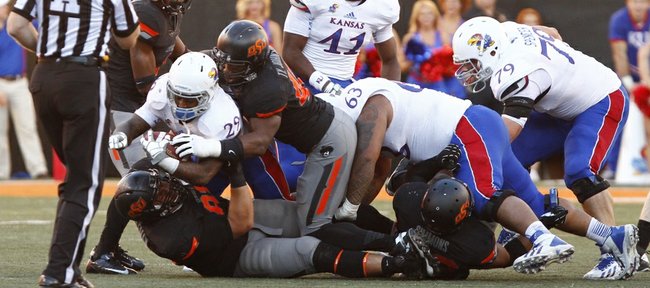 Kansas running back James Sims is brought down for a loss by Oklahoma State defenders Tyler Johnson and James Castleman, bottom, during the second quarter on Saturday, Nov. 9, 2013 at Boone Pickens Stadium in Stillwater, Oklahoma.