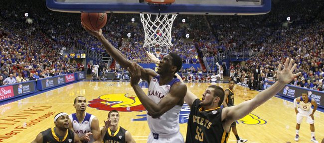 Kansas center Joel Embiid dips under the bucket for a reverse layup after being fouled by Toledo center Nathan Boothe during the second half on Monday, Dec. 30, 2013 at Allen Fieldhouse.