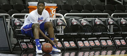 Kansas center Joel Embiid ties a shoe during practice for the Jayhawks' opening NCAA basketball game in the Big 12 men's tournament in Kansas City, Mo., Wednesday, March 12, 2014.