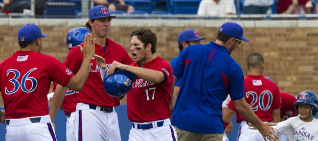 Kansas junior Michael Suiter (17) is met by teammates in front of the dugout after scoring a run during Kansas' game against West Virgina, Sunday afternoon at Hoglund Ballpark. The Jayhawks swept the three game series by holding off the Mountaineers, 9-8, in the final game.