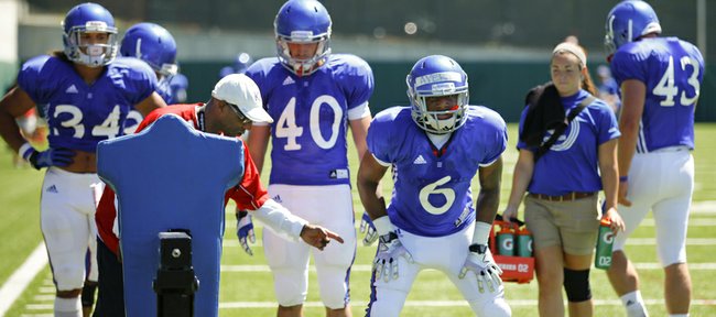 Kansas' Corey Avery (6) takes some instruction from running backs coach Reggie Mitchell during practice on Tuesday, Aug. 12, 2014.