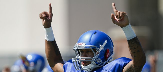 Kansas receiver Nick Harwell raises his arms as he and his teammates stretch out during practice on Tuesday, Aug. 12, 2014.