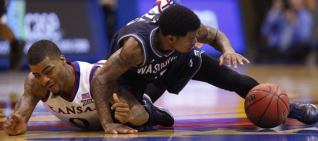 Kansas guard Frank Mason slides across the floor with Washburn guard Kyle Wiggins while going for a loose ball during the second half on Monday, Nov. 3, 2014 at Allen Fieldhouse.