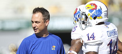 Kansas co-offensive coordinator Eric Kiesau works with quarterback Michael Cummings and receiver Nick Harwell before kickoff against Baylor on Saturday, Nov. 1, 2014 in Waco, Texas.