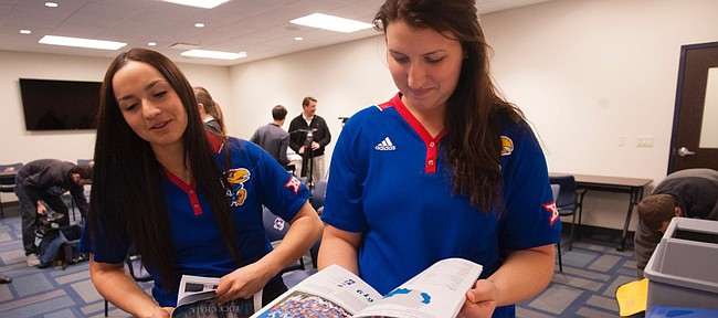 Kansas University softball players Chanin Naudin, left, and Maddie Stein glance at the Jayhawks' media guide Thursday afternoon, January 29, 2015, at Rock Chalk Park.