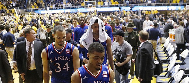 Kansas guard Frank Mason III (0), Perry Ellis (34) and Landen Lucas, background right, walk off the court as West Virginia fans storm the court after defeating the Jayhawks 62-61 Monday, February 16, 2105  in Morgantown, W.V.