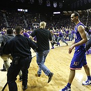 Journal-World photographer Nick Krug has learned a thing or two about how to prepare and navigate a court-storming, such as this one when Kansas State fans rushed the court at Bramlage Coliseum on Feb. 23 after the Wildcats defeated the Jayhawks. At right, a fan runs into KU's Jamari Traylor, which caused a national discussion about the safety risks posed by court-storming. 