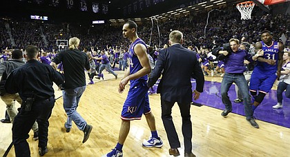 Journal-World photographer Nick Krug has learned a thing or two about how to prepare and navigate a court-storming, such as this one when Kansas State fans rushed the court at Bramlage Coliseum on Feb. 23 after the Wildcats defeated the Jayhawks. At right, a fan runs into KU's Jamari Traylor, which caused a national discussion about the safety risks posed by court-storming. 