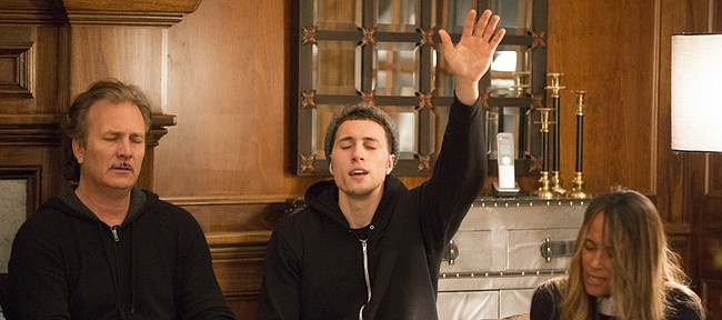 Christian Garrett, a walk-on senior for the Kansas University basketball team, raises his hand in worship during a bible study group with his mother, Cynthia Garrett, right, and his stepfather, Roger Charles, on Thursday, Feb. 26, 2015, in their Lawrence home.