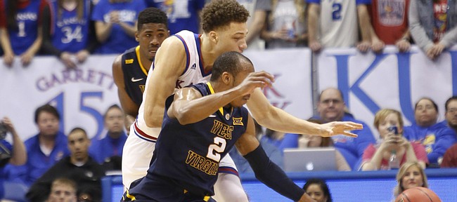 West Virginia guard Daxter Miles Jr. (4) jumps in front of  Kansas guard Brannen Greene (14) for a steal during the Jayhawks game against the West Virginia Mountaineers Tuesday, March 4, 2015 at Allen Fieldhouse..