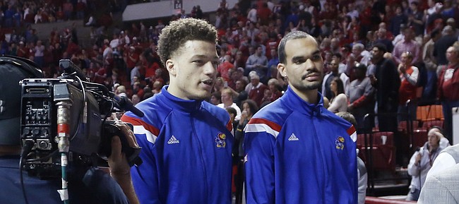 Kansas guard Brannen Greene, left, and forward Perry Ellis walk off the court behind assistant coach Norm Roberts after the Jayhawks 75-73 loss to the Oklahoma Sooners Saturday in Norman. Neither player played in the game. Greene was suspended for the game and Ellis was injured