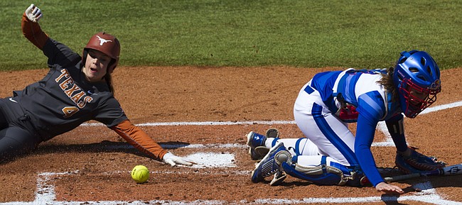 Texas sophomore Devon Tunning (4) slides safely into home for a score while Kansas freshman catcher Jessie Roane looks for the ball during Kansas' game against Texas Saturday afternoon at Arrocha Ballpark.
