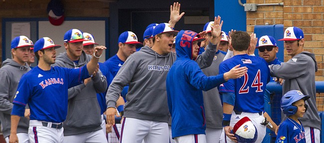 Kansas players line up outside of their dugout to greet junior Colby Wright (24) after he and senior Connor McKay scored on a two-run double by senior Blair Beck during the fourth inning of the Jayhawks' game against Oklahoma State Sunday afternoon at Hoglund Ballpark. 