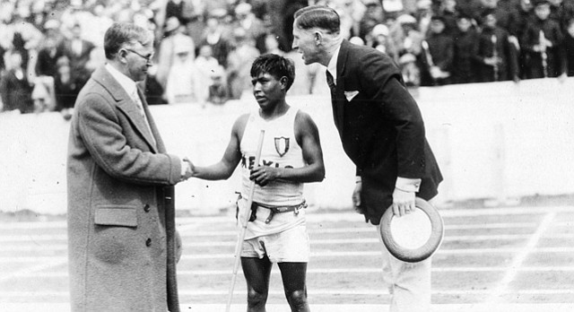 A Tarahumara Indian athlete, identified on the back of the photo as Jose Torres, shakes the hand of former Lawrence mayor R. C. Rankin, standing next to F. C. "Phog" Allen. Torres won a foot race from Kansas City to Lawrence that ended in Memorial Stadium during the 1927 Kansas Relays.