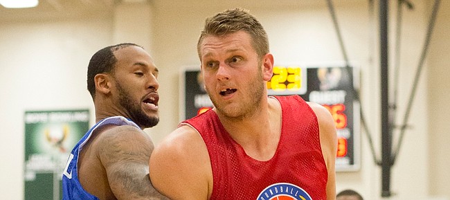 Red team's Cole Aldrich makes a move around Travis Releford the annual Rock Chalk Roundball Classic basketball game Thursday evening at Free State High School. Proceeds from the game, which features former Kansas University players, benefits families fighting cancer. This year's beneficiaries were Levi Ross and Dade Cannon.