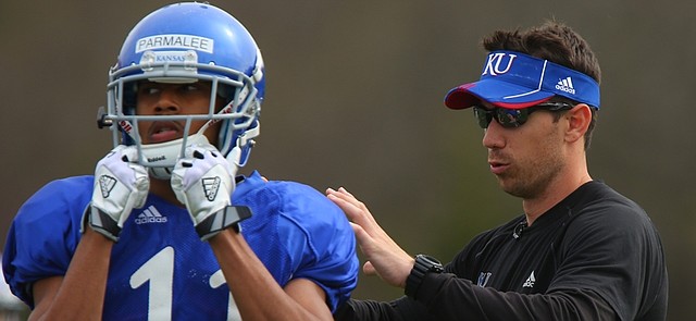 Kansas wide receivers coach Klint Kubiak works with Tre Parmalee during practice on Tuesday, April 14, 2015