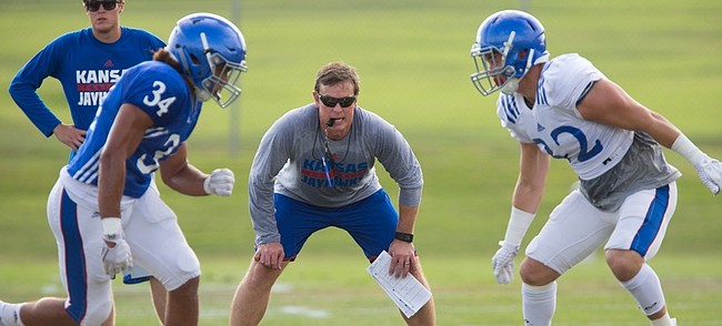 Kansas linebackers coach Kevin Kane gets down as he watches linebackers Aaron Plump (34) and Schyler Miles square off to hit on Monday, Aug. 17, 2015 at the fields south of Anschutz Pavilion.