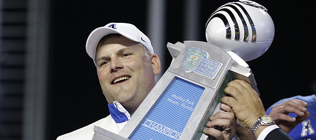 In this Dec. 22, 2014 file photo, Memphis head coach Justin Fuente holds up the trophy after Memphis defeated Brigham Young 55-48 in double overtime during the Miami Beach Bowl football game in Miami.