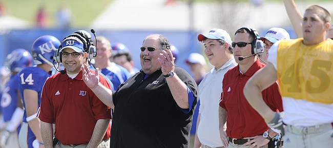 Former Kansas University head coach Mark Mangino, now the offensive coordinator at Iowa State, has a laugh on the sidelines during the second half of the 2009 Spring Game at Memorial Stadium, as current KU coach David Beaty (in red, at right), then the Jayhawks' wide receivers coach, stands nearby.
