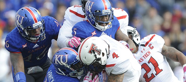 Kansas linebackers Courtney Arnick (28) and Marcquis Roberts (5), and defensive end Dorance Armstrong Jr. (46) work to bring down Texas Tech running back Justin Stockton (4) during the first quarter on Saturday, Oct. 17, 2015 at Memorial Stadium.