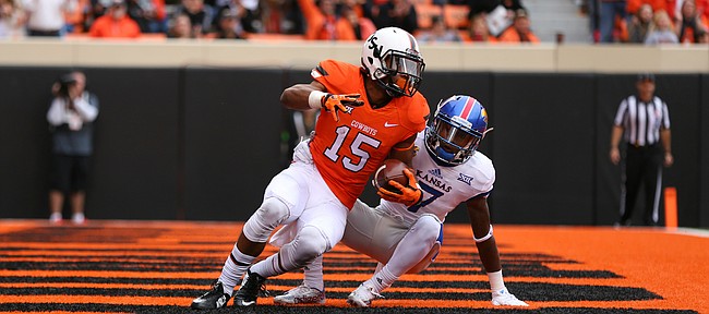 Oklahoma State wide receiver Chris Lacy (15) rolls onto his feet after a touchdown while covered by Kansas cornerback Derrick Neal (7) during the third quarter on Saturday, Oct. 24, 2015 at T. Boone Pickens Stadium in Stillwater, Okla.