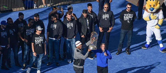 Kansas City Royals’ Salvador Perez helps general manager Dayton Moore hold the World Series trophy during a rally to celebrate the Royals’ Championship Tuesday in Kansas City, Missouri. Also on Tuesday, Kansas University head coach David Beaty pointed to the Royals as a blueprint for the future of the Kansas football program.