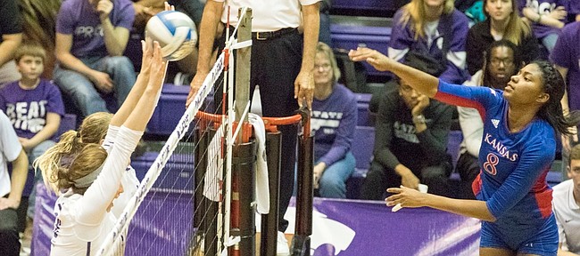 Kansas sophomore Kelsie Payne (8) sends the ball flying past a pair of Kansas State blockers during their volleyball match Wednesday, Nov. 25, 2015, at Ahearn Field House.