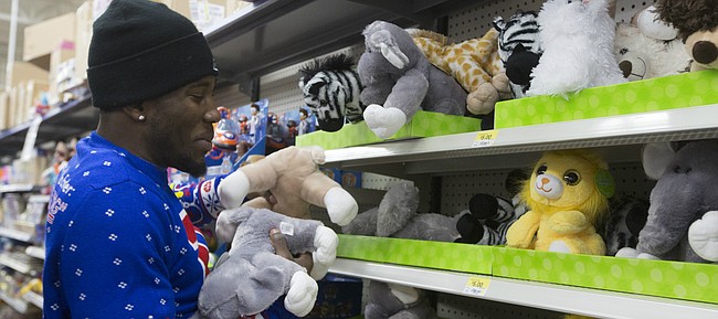 Kansas senior Jamari Traylor grabs an arm full of stuffed animals while shopping for a local family at Wal-Mart, 3300 Iowa Street, on Wednesday evening.