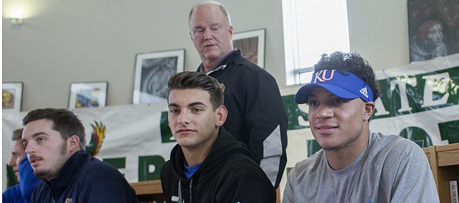 Free State High senior Bryce Torneden, right, is introduced by FSHS football coach Bob Lisher, standing, before Torneden signed a letter of intent to play at Kansas University next year. Also signing letters of intent with colleges Wednesday at FSHS, from left, are Firebirds Garrett Swisher, left, with Highland Community College, and Drew Tochtrop, with Hutchinson Community College.