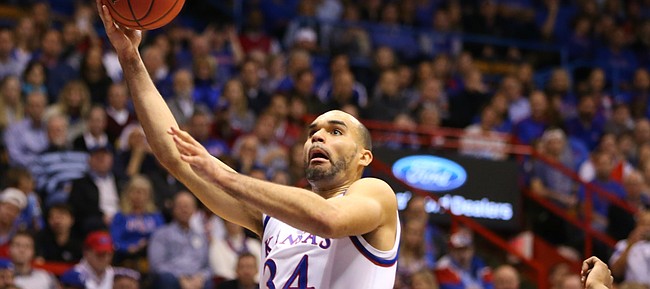 Kansas forward Perry Ellis (34) gets in for a bucket past West Virginia forward Elijah Macon (45) and forward Esa Ahmad (23) during the first half, Tuesday, Jan. 9, 2016 at Allen Fieldhouse.